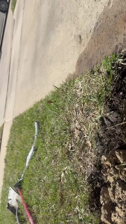 A real Waterline French drain trench mid-install in Texas black clay: fabric-lined and ready for washed rock over sock-wrapped Schedule 40 PVC
