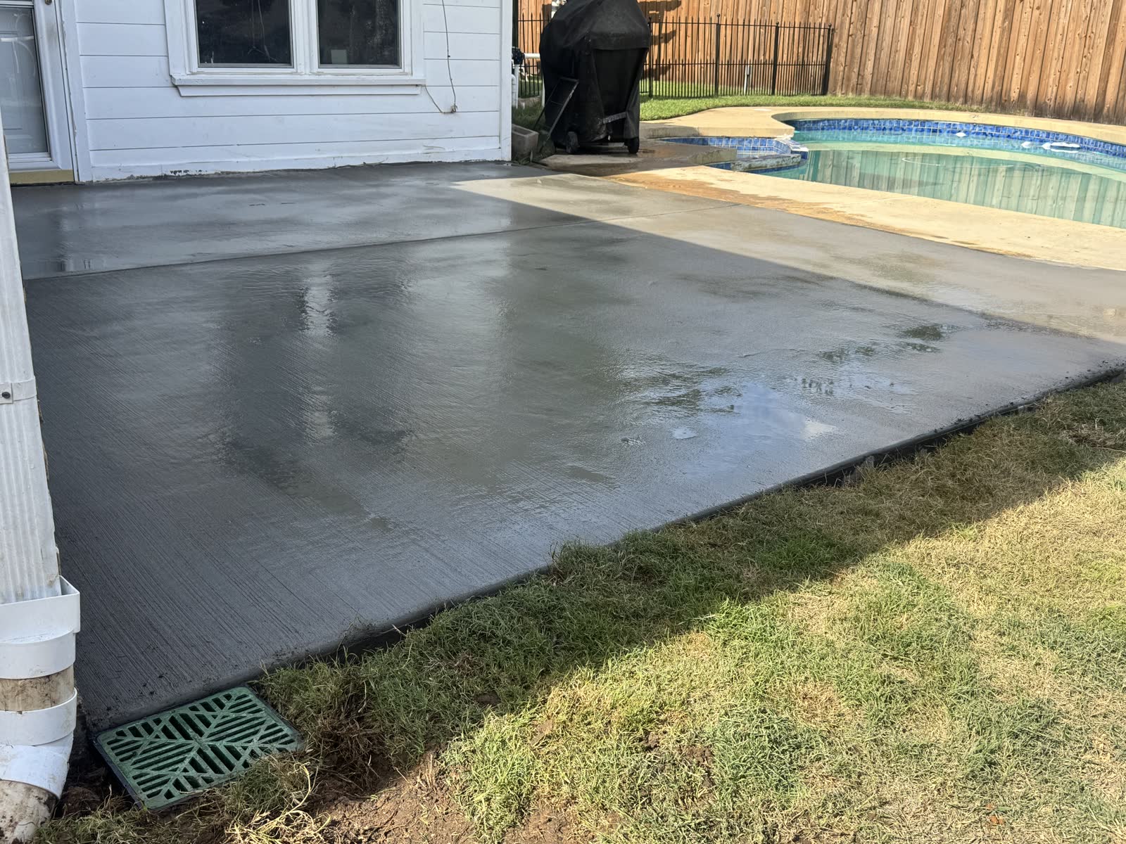 Completed poolside concrete and surface drain beside a downspout